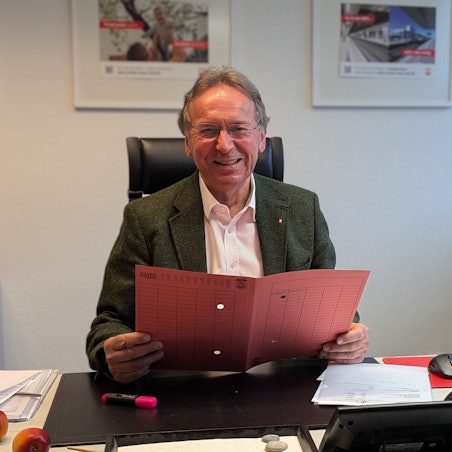 Das Foto zeigt Caritas-Vorstand Peter Altmayer mit einer Umlaufmappe an seinem Schreibtisch.