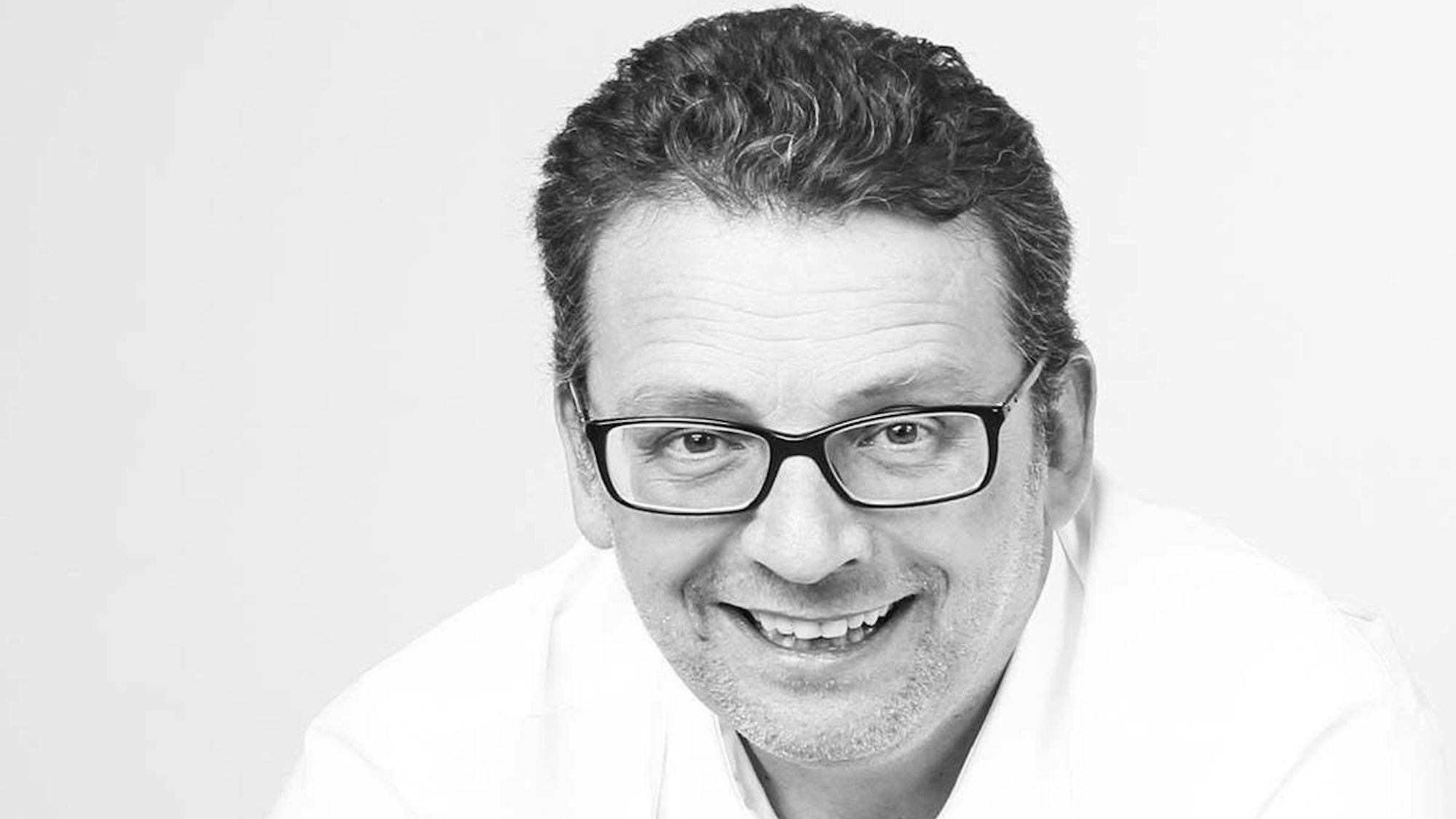 Ein Mann mit Brille lächelt.