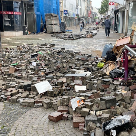 Straßensteine, die durch die Flut aus der Erde gehoben wurden, liegen in der Euskirchener Fußgängerzone. (Archivfoto)