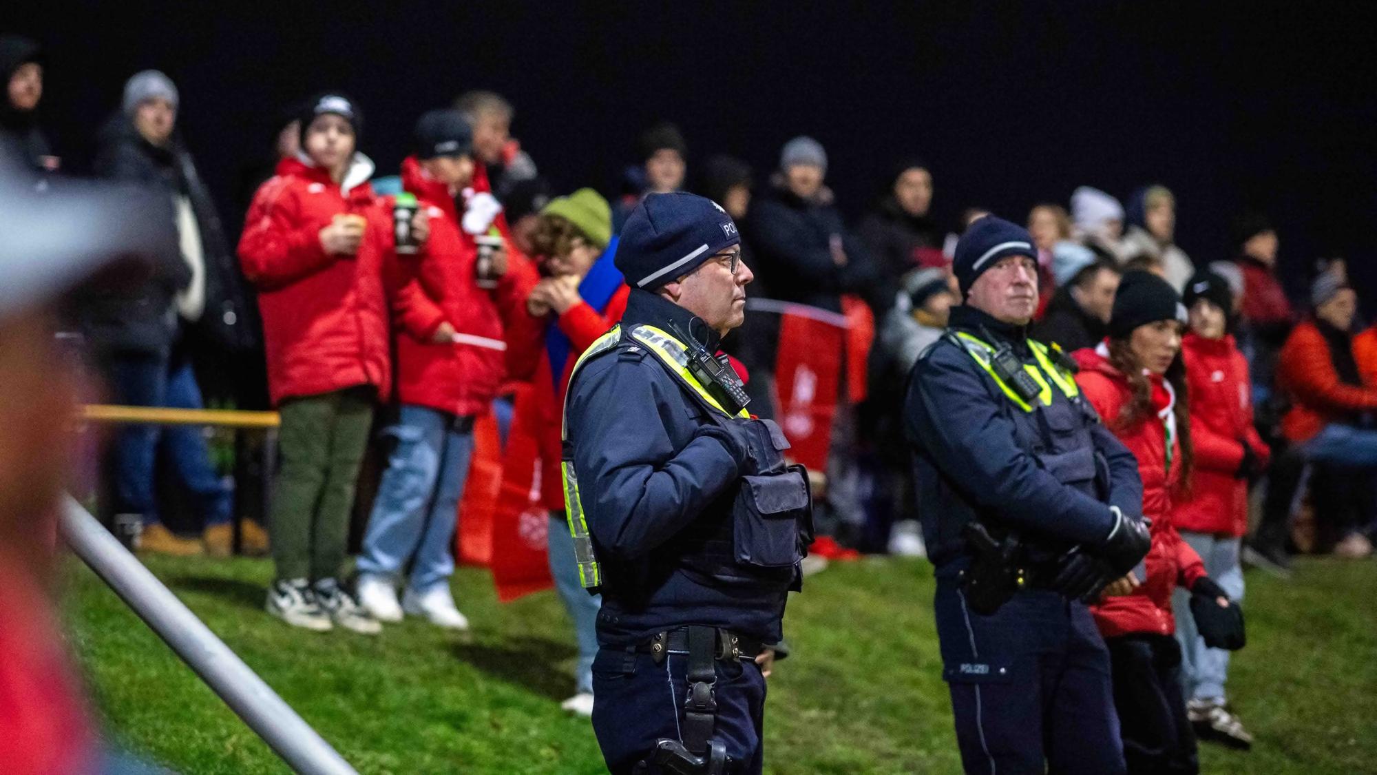 Polizisten stehen am Spielfeldrand und beobachten das Spiel.