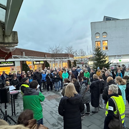 Menschen stehen auf einem Platz.