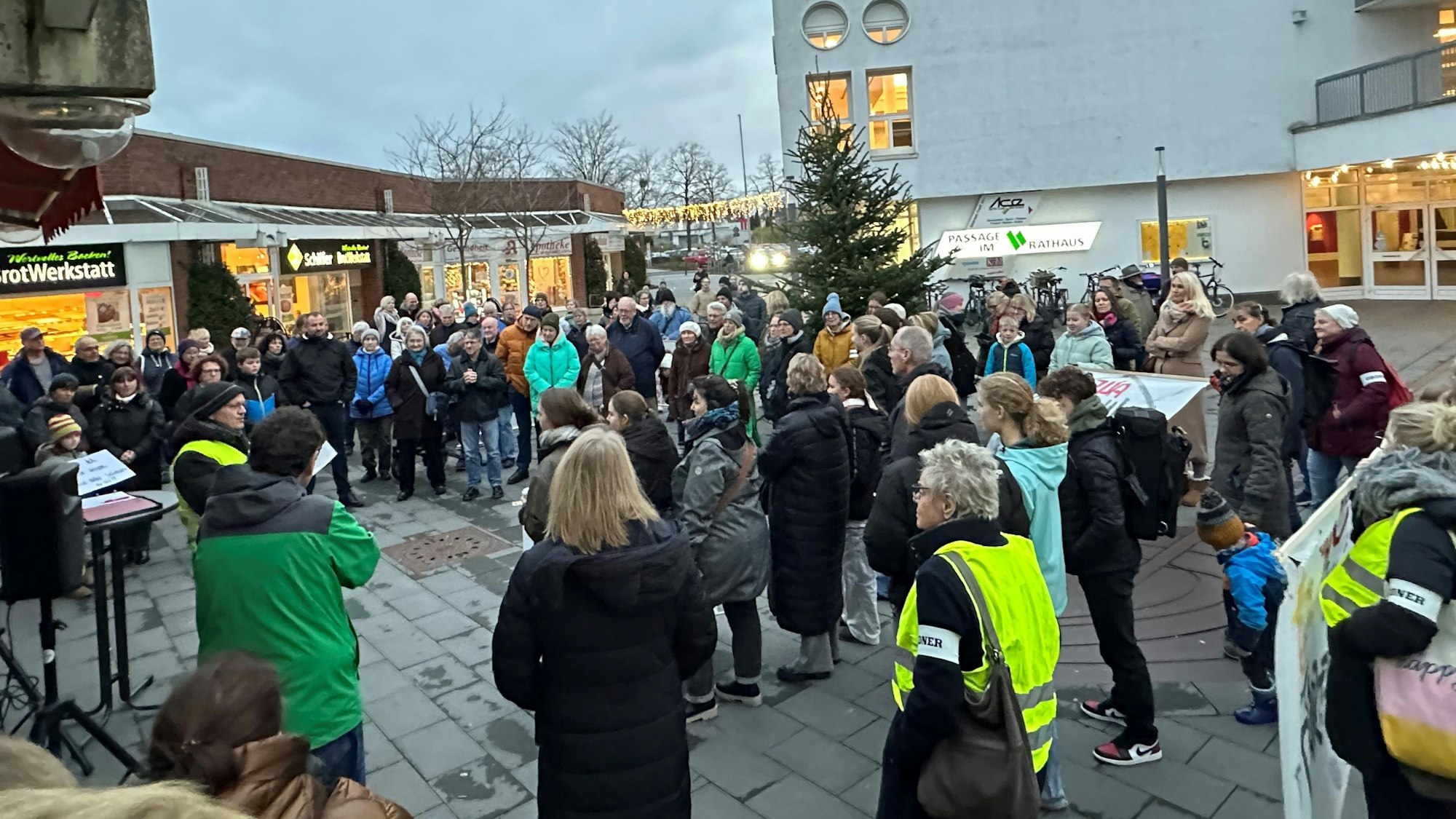 Zu sehen sind etwa 70 Menschen bei einer Demonstration, die in einem Kreis stehen.