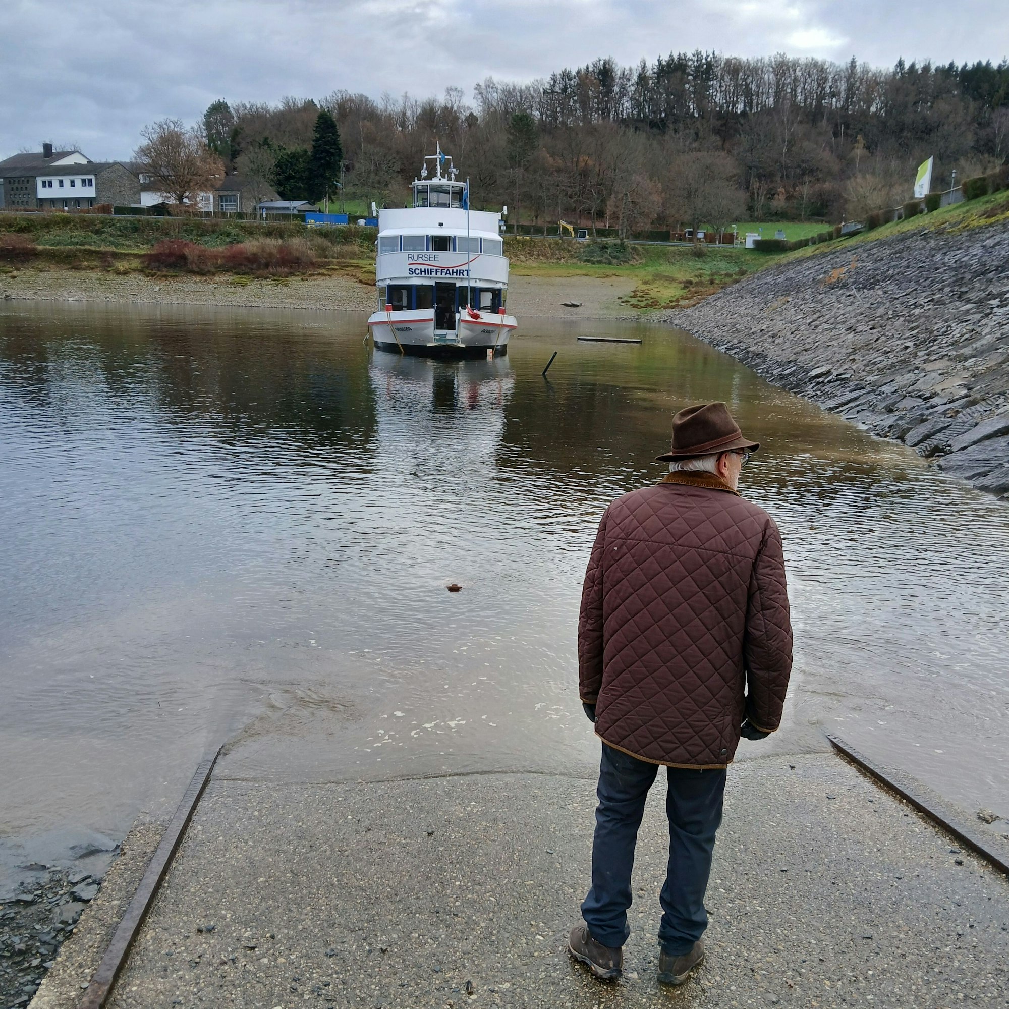Der Reeder steht auf der Rampe, die Aachen treibt in einiger Entfernung in der Nähe einer Steinböschung im flachen Wasser.