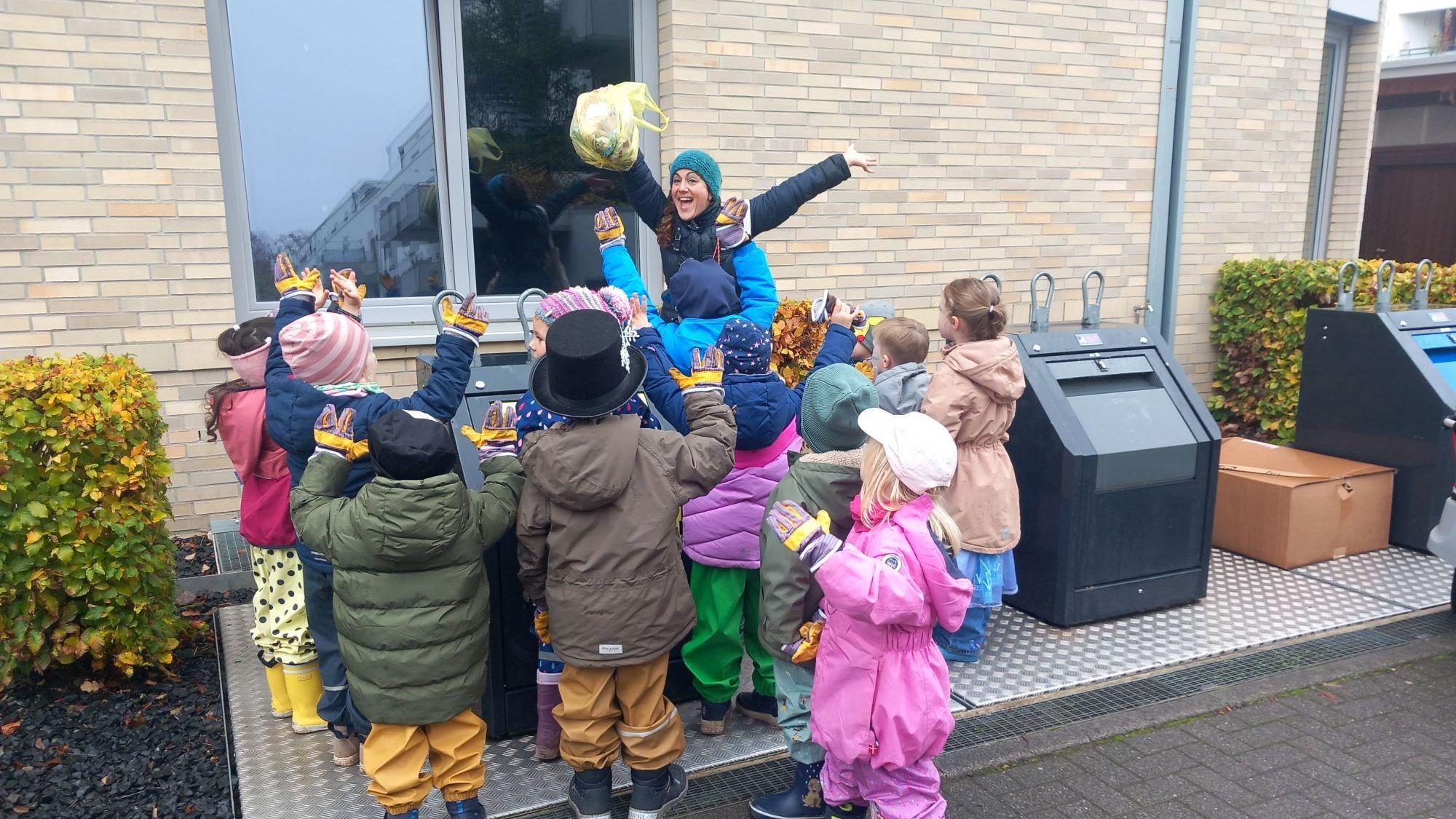 Kinder stehen mit Silke Heiser vor verschiedenen Mülltonnen.