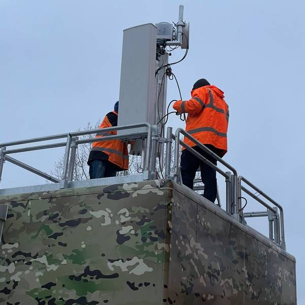 Zwei Techniker arbeiten an einem Sendemast.