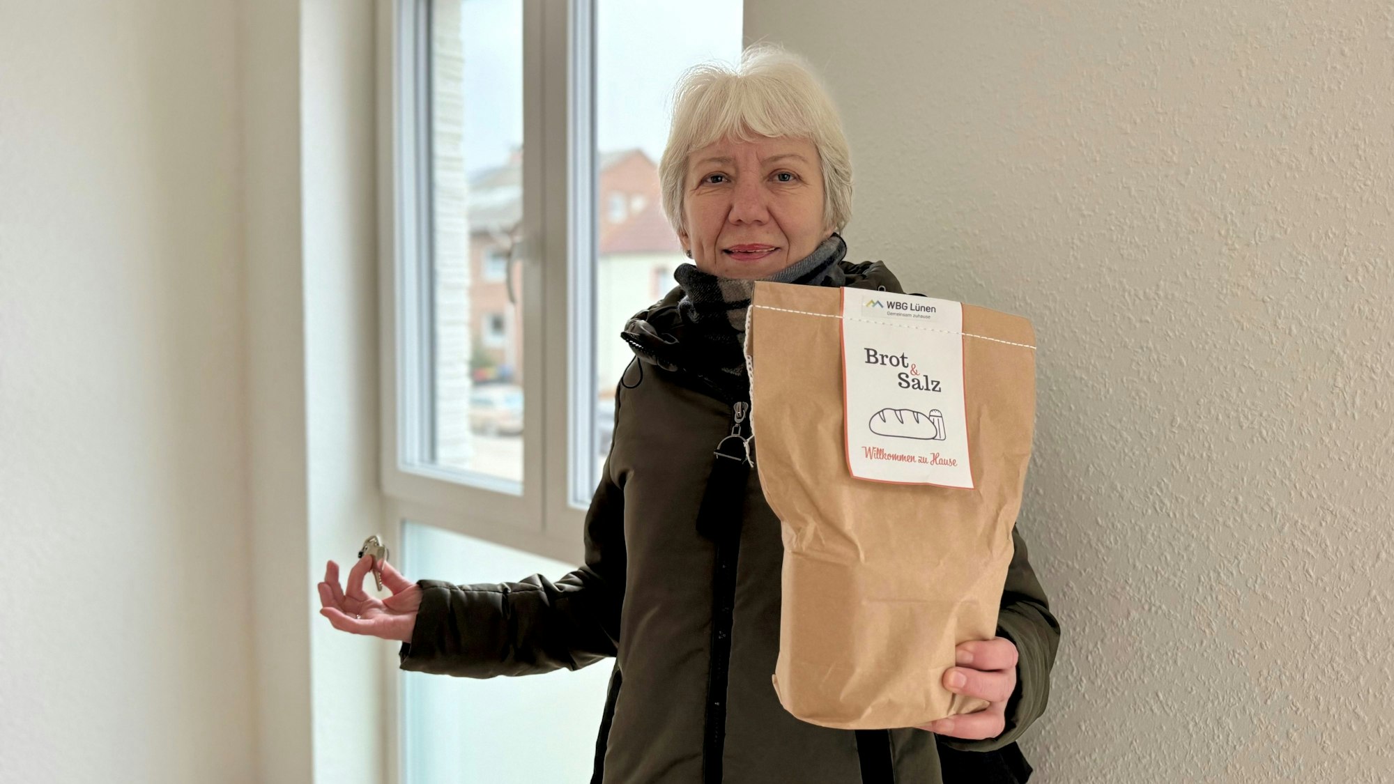 Hanna Ickeroolt steht vor einem Fenster und hält Schlüssel und ein Päckchen mit Brot und Salz in der Hand