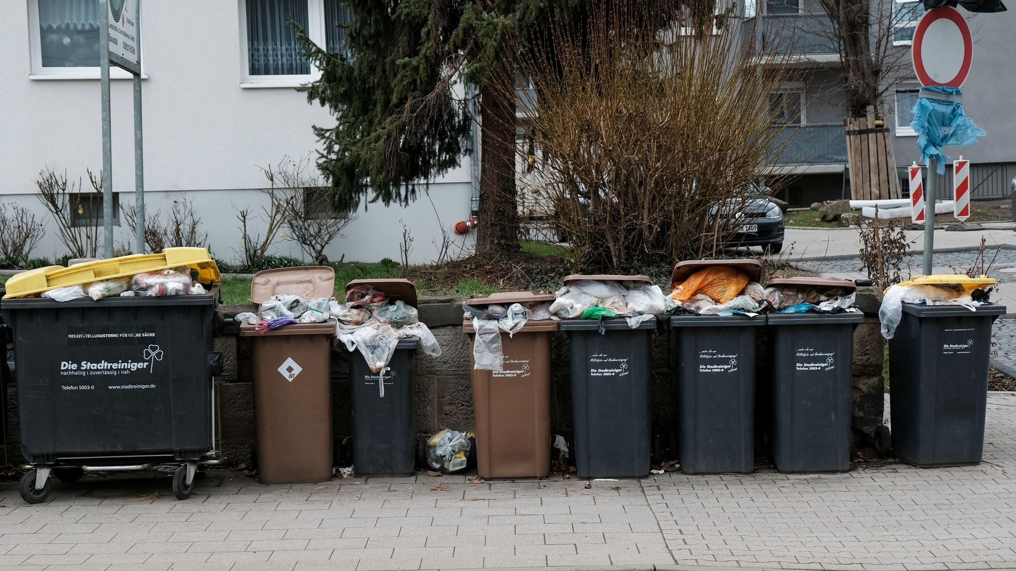 Mülltonnen vor einem Mietshaus an der Straße quillen über