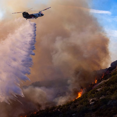 10.12.2024, USA, Malibu: Ein Löschhubschrauber des Los Angeles County wirft Wasser auf das Franklin Fire, um Häuser an der nahe gelegenen Costa Del Sol in Malibu zu schützen. Foto: Jill Connelly/ZUMA Press Wire/dpa +++ dpa-Bildfunk +++
