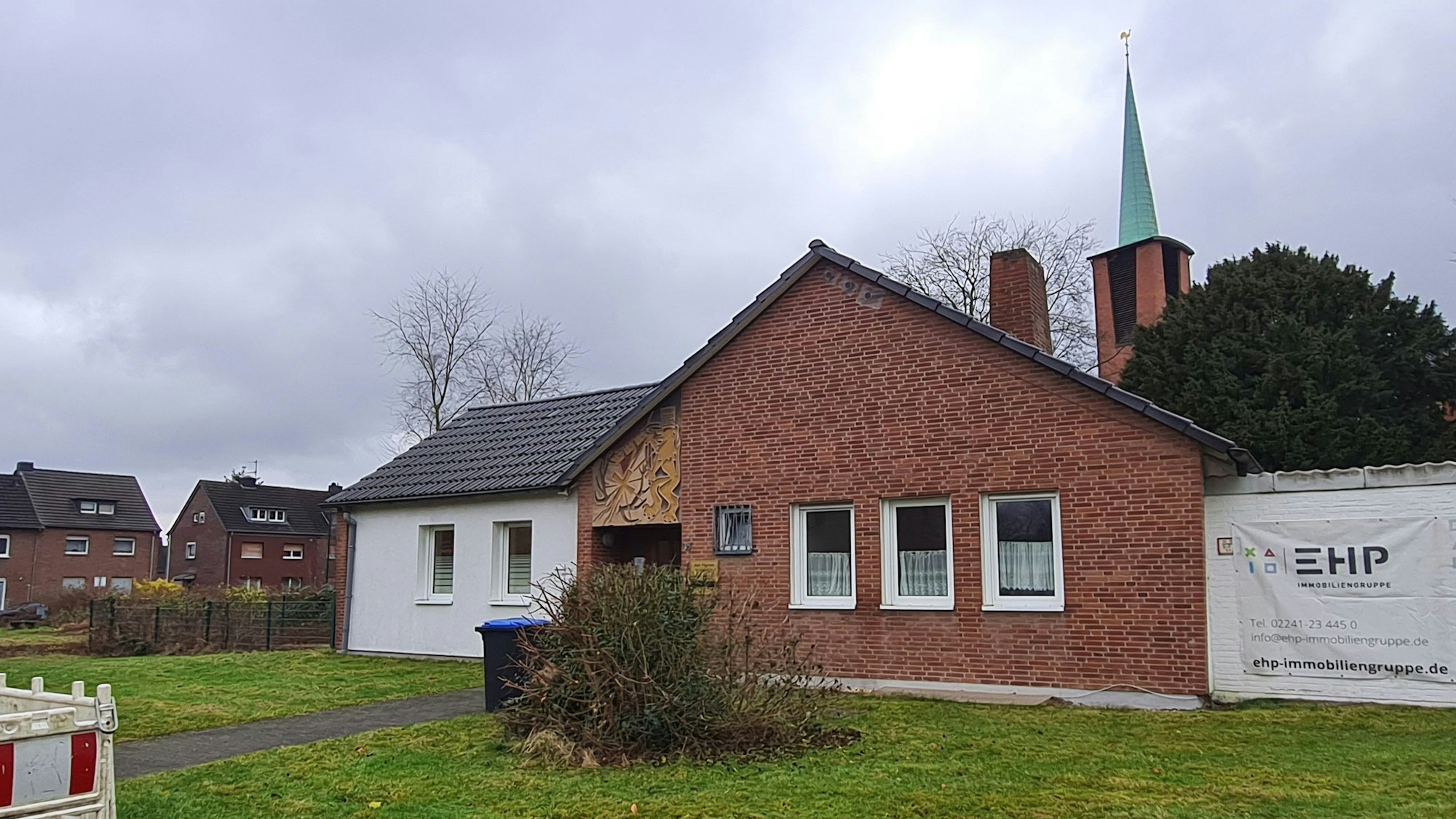 Das Foto zeigt ein altes Pfarrhaus vor der Kirche.