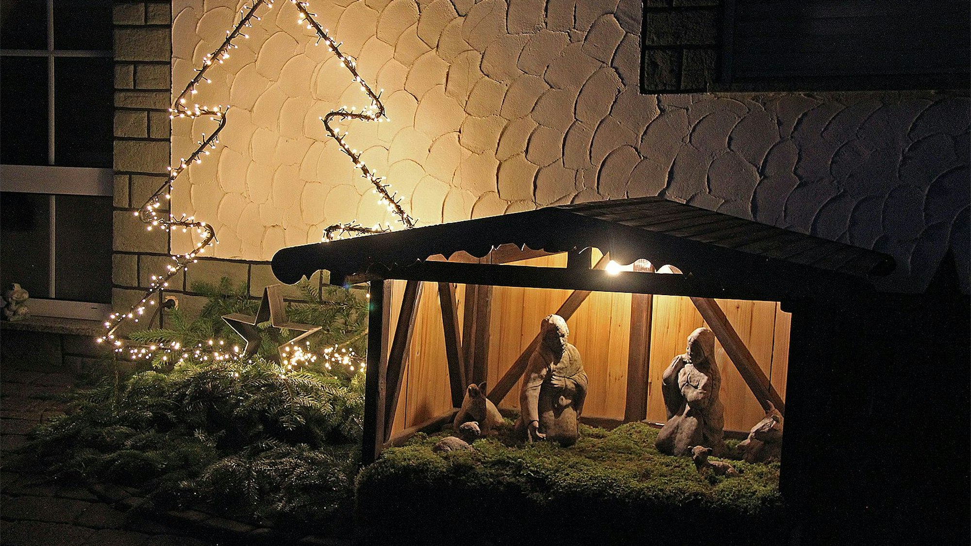 Die Krippe steht vor dem Haus und ist idyllisch beleuchtet.