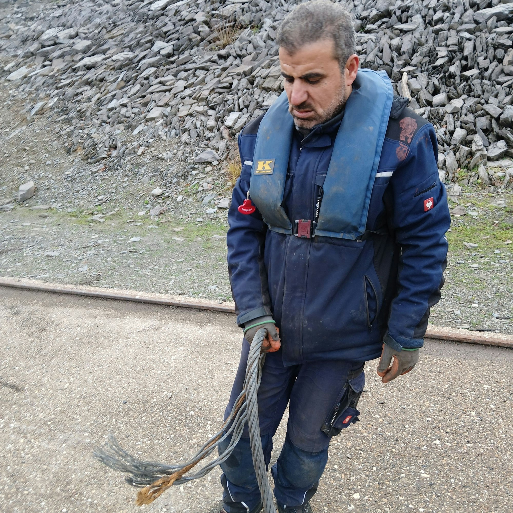 Der Mitarbeiter hält das dicke Stahlseil in der Hand.
