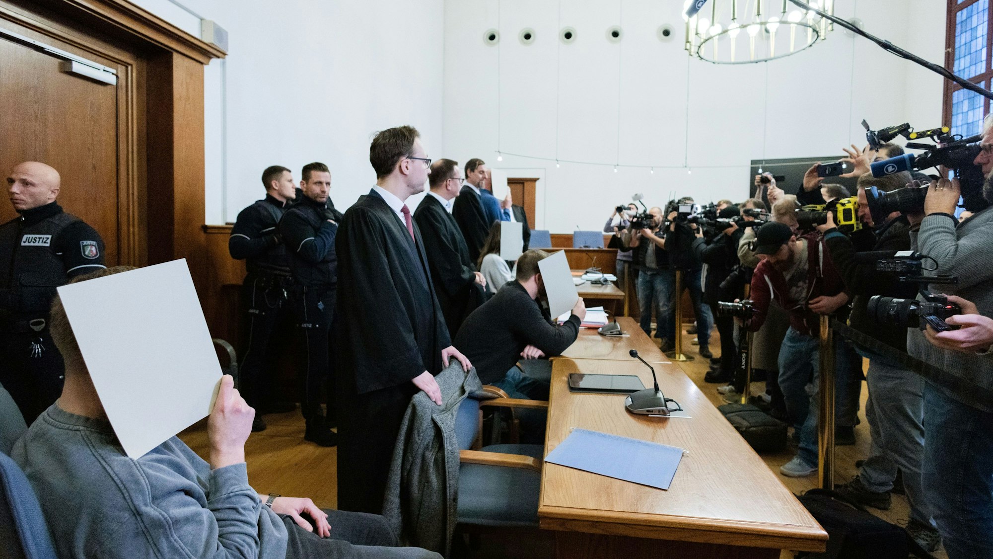 Die fünf angeklagten Polizeibeamtinnen und -beamten sitzen zwischen ihren Anwälten im Gerichtssaal des Landgerichts.