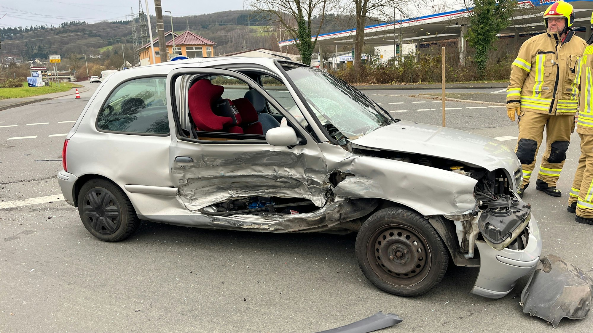 Ein Kleinwagen steht erheblich beschädigt auf einer Straße.