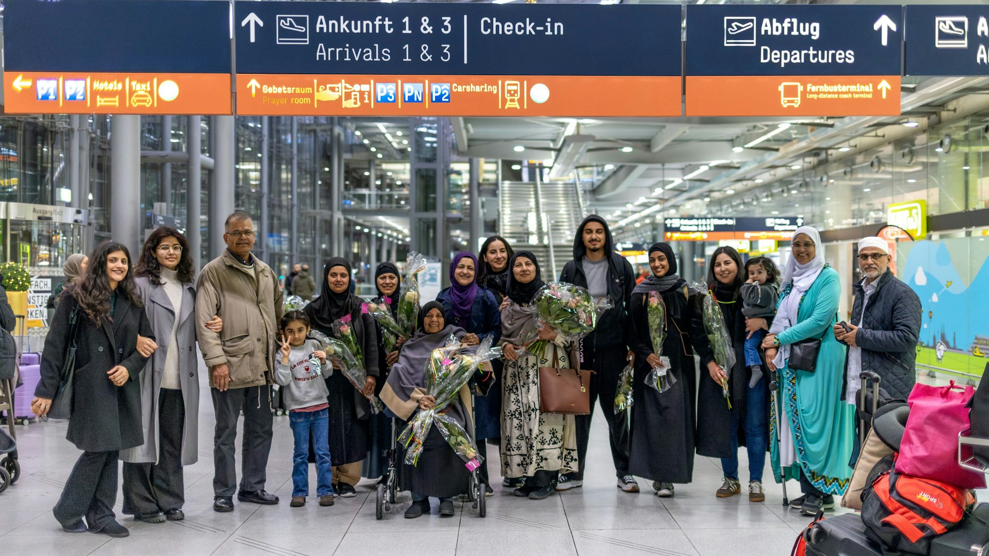 Eine Gruppe von Menschen steht in der Ankunftshalle des Flughafens.