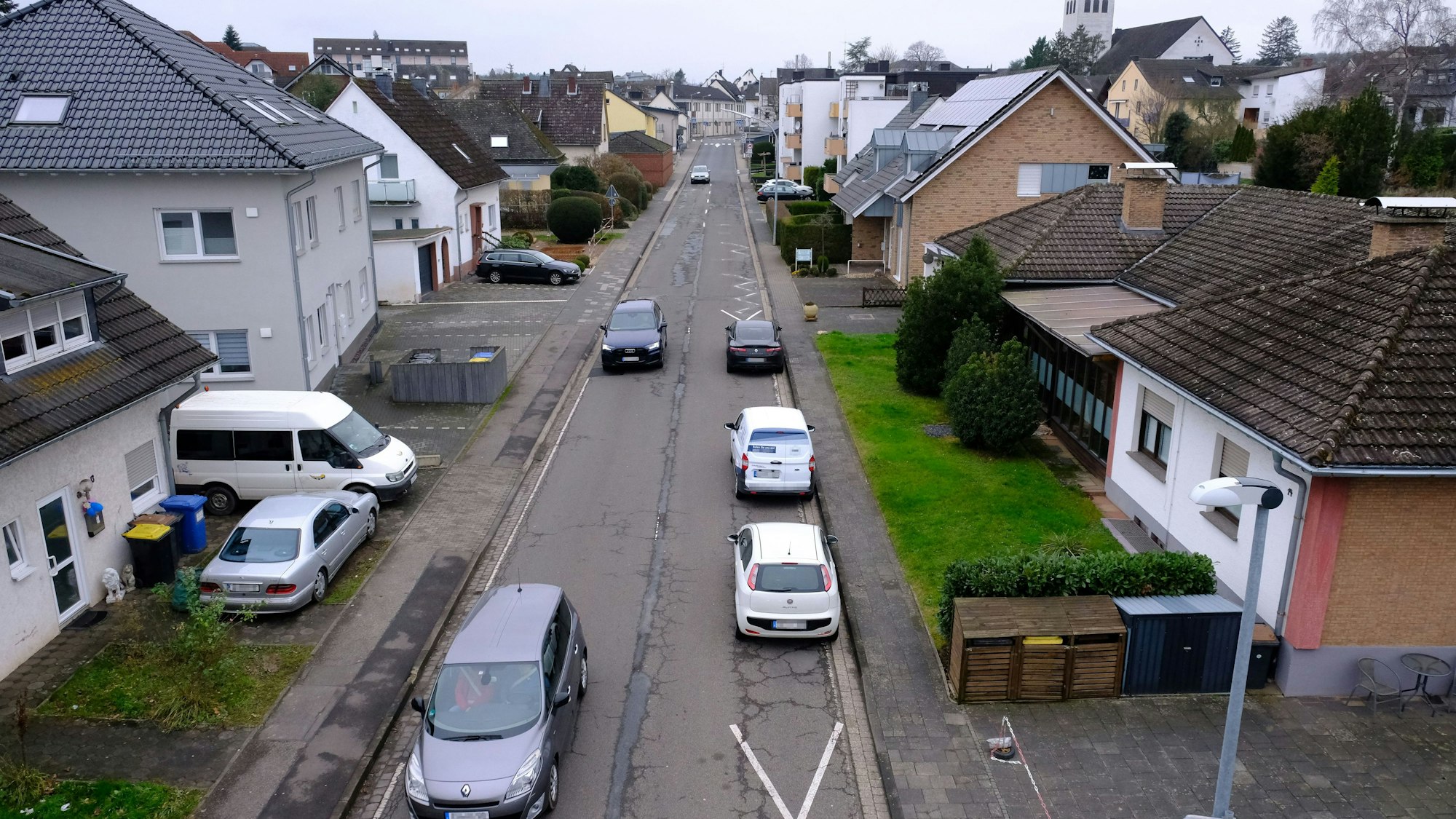 Die Feytalstraße in Mechernich führt von der Ortsmitte zum Schulzentrum. Am rechten Straßenrand parken drei Autos auf der Fahrbahn.