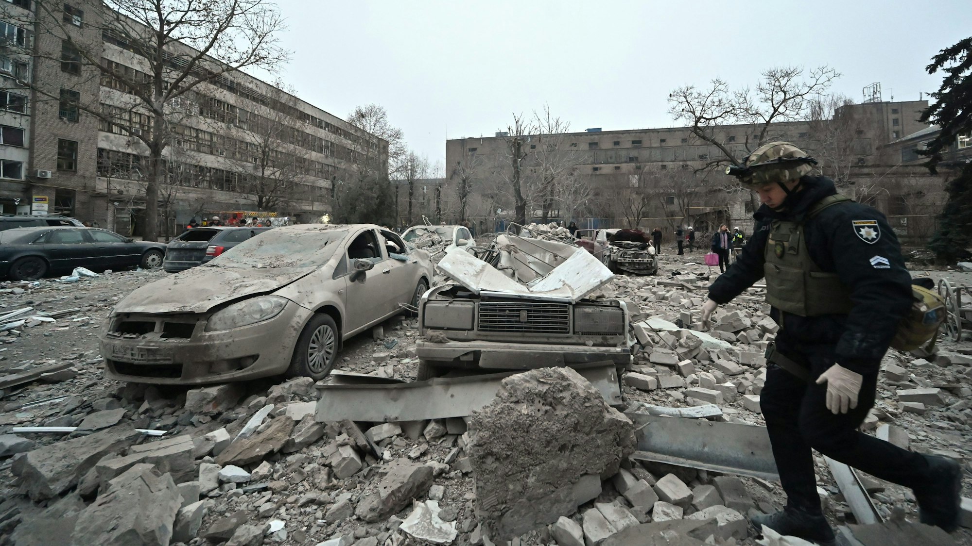 Ein Polizist geht an Autos vorbei, die nach einem russischen Raketenangriff in Saporischschja im Südosten der Ukraine von den Trümmern zerquetscht wurden.