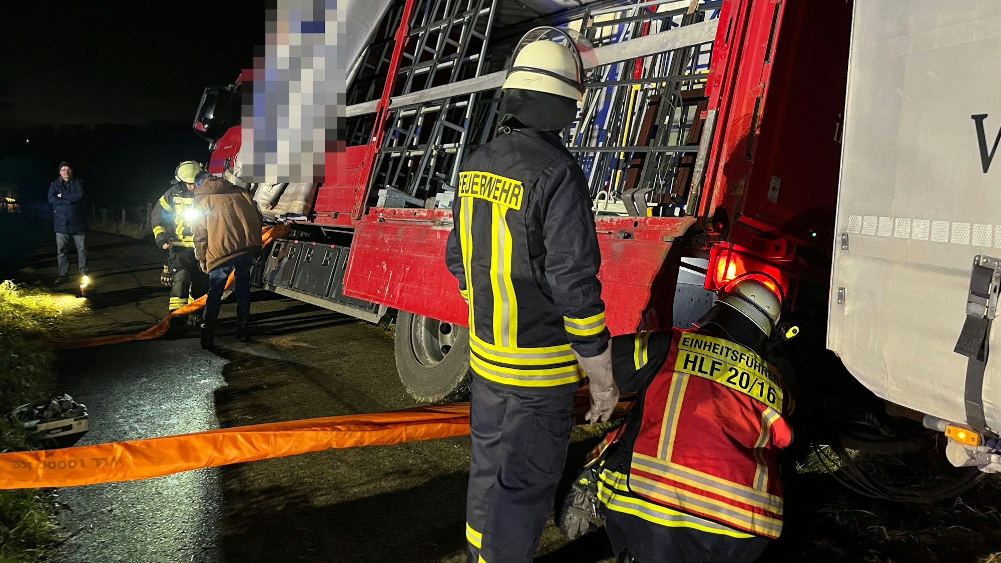 Ein Lastwagen ist von einem Feldweg abgerutscht, Feuerwehrleute bringen Gurte an.