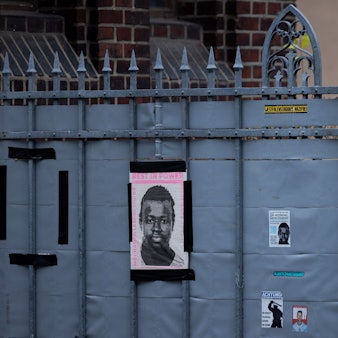 Dortmund: Plakate und eine Plakette erinnern am Tatort (hinter dem Zaun) an den 16-jährigen Senegalesen Mouhamed Drame. Am 19.12.2023 begann der Prozess nach tödlichen Polizeischüssen auf einen jungen Flüchtling. Der Jugendliche aus dem Senegal war am 8. August 2022 auf dem Gelände einer Jugendhilfeeinrichtung erschossen worden.