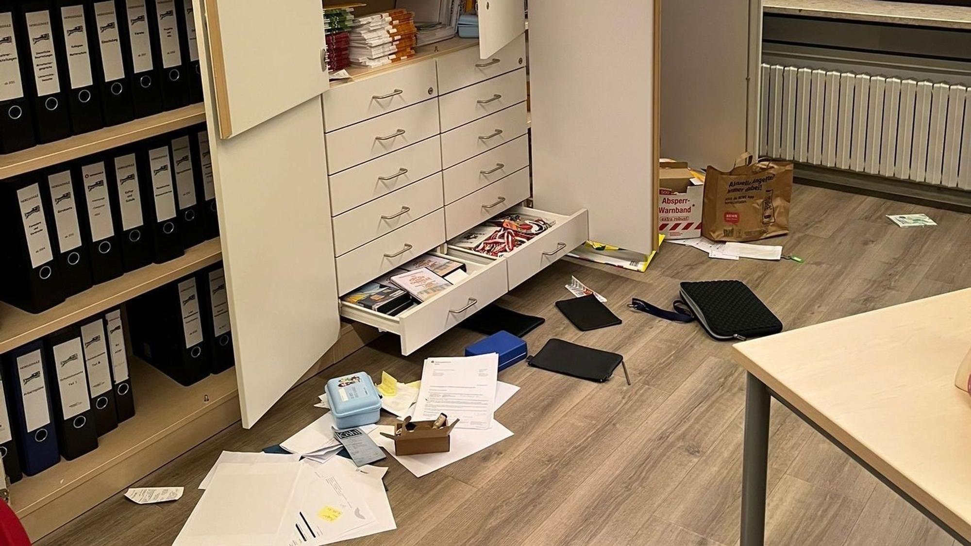 Zu sehen ist ein aufgebrochener Schrank, vor dem Gegenstände liegen.
