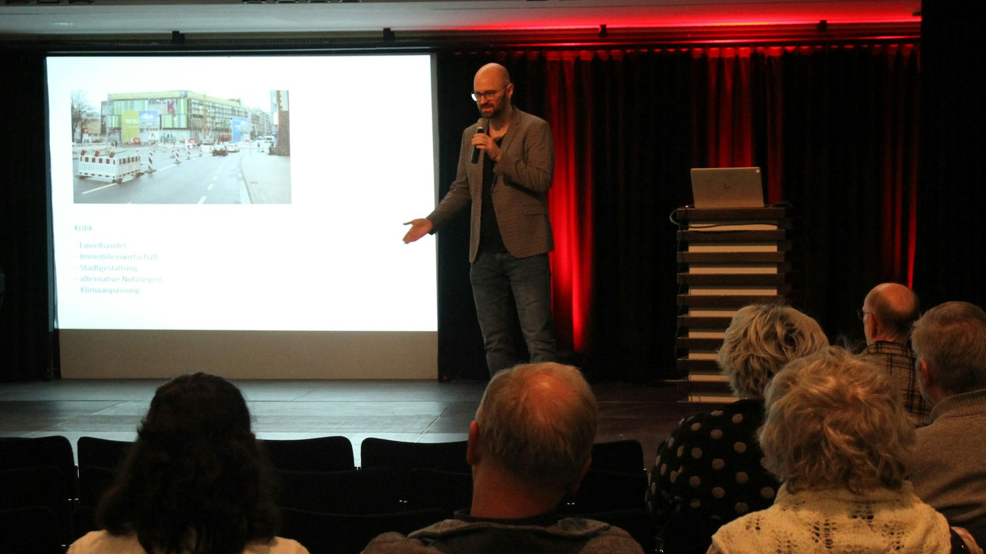 Ein Mann vor einer Leinwand, im Vordergrund Zuhörer