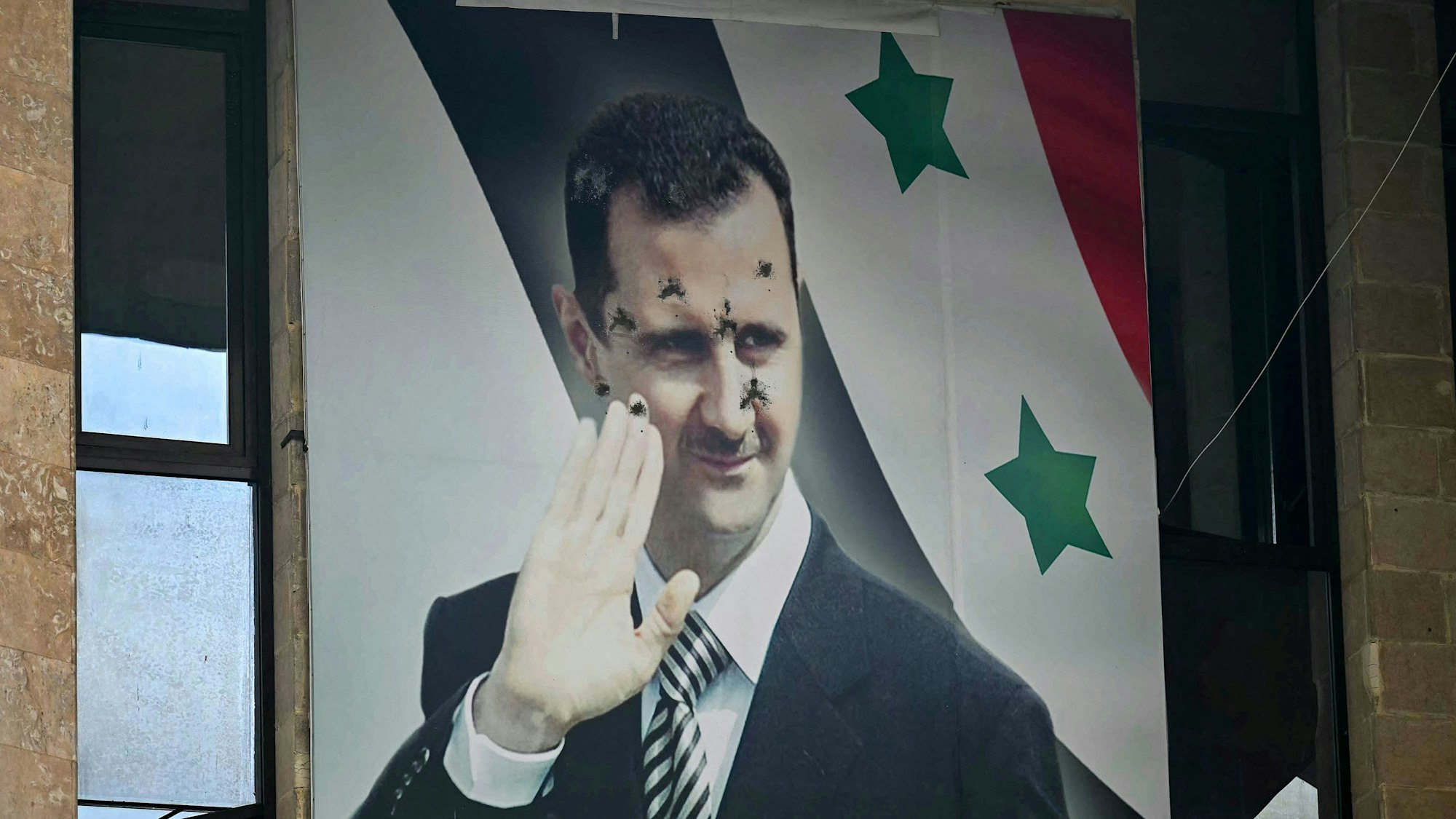 Ein zerschossenes Plakat des gestürzten Präsidenten Assad hängt in Aleppo.