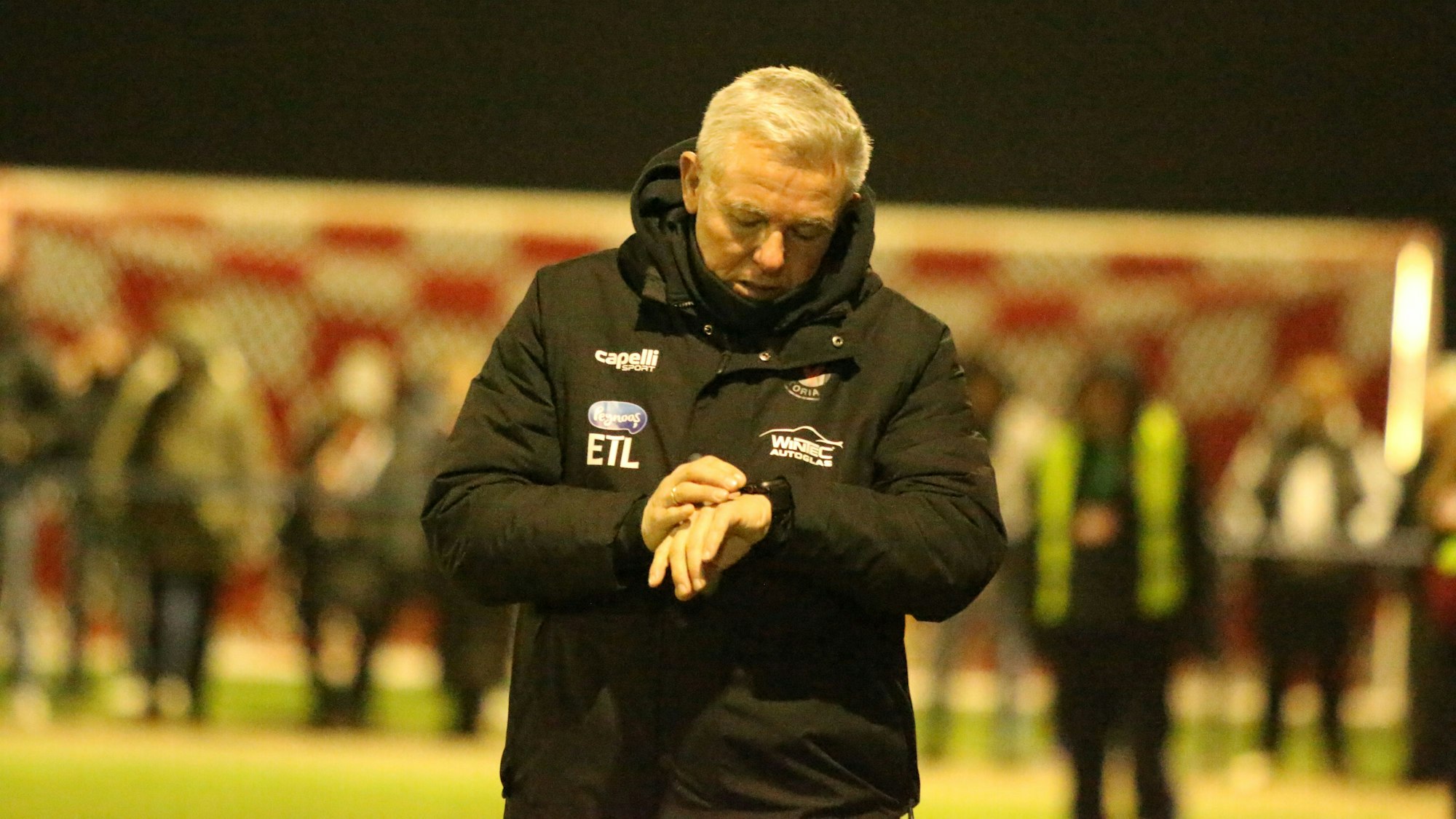 Viktoria Köln Trainer Olaf Janßen schaut auf die Uhr.
