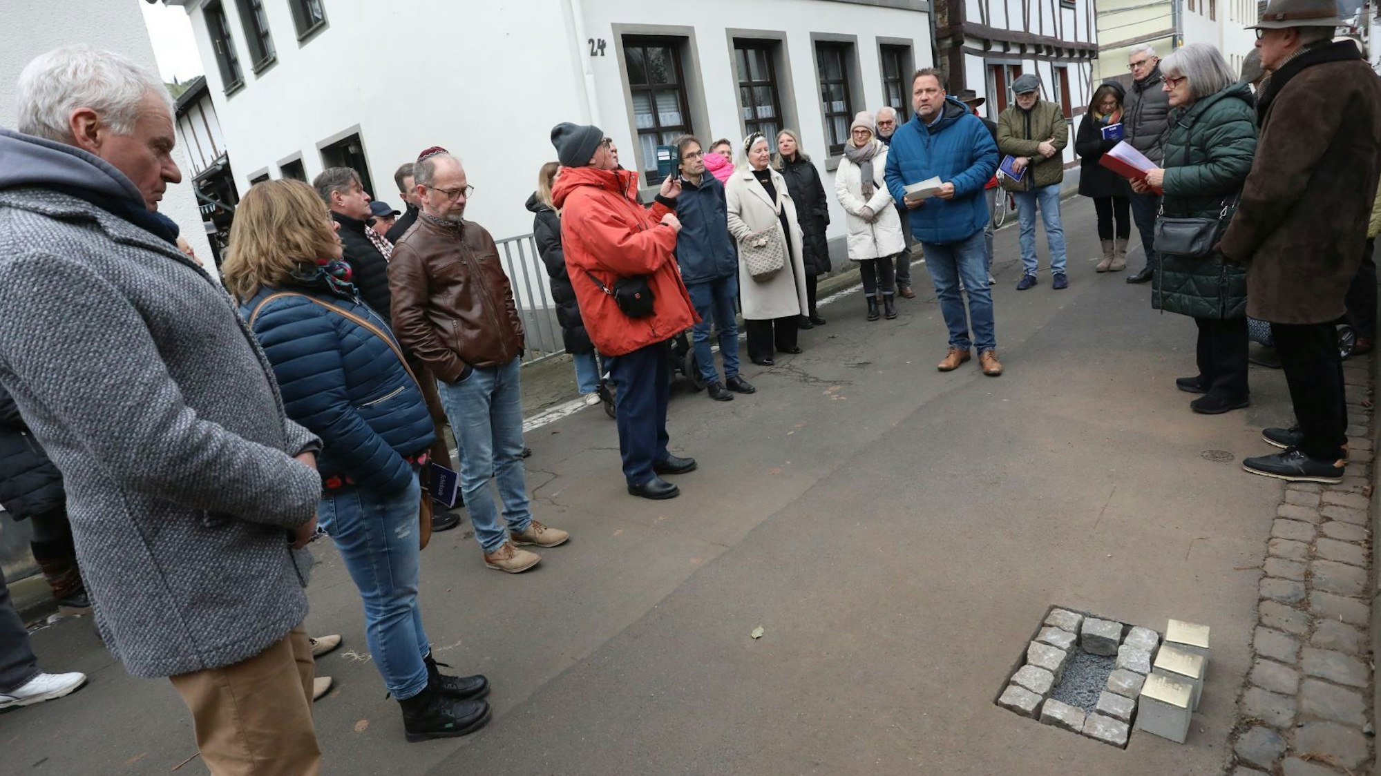 Mehrere Menschen auf einer Straße, am Rand liegen Messingsteine, die in die Straße eingesetzt werden sollen.