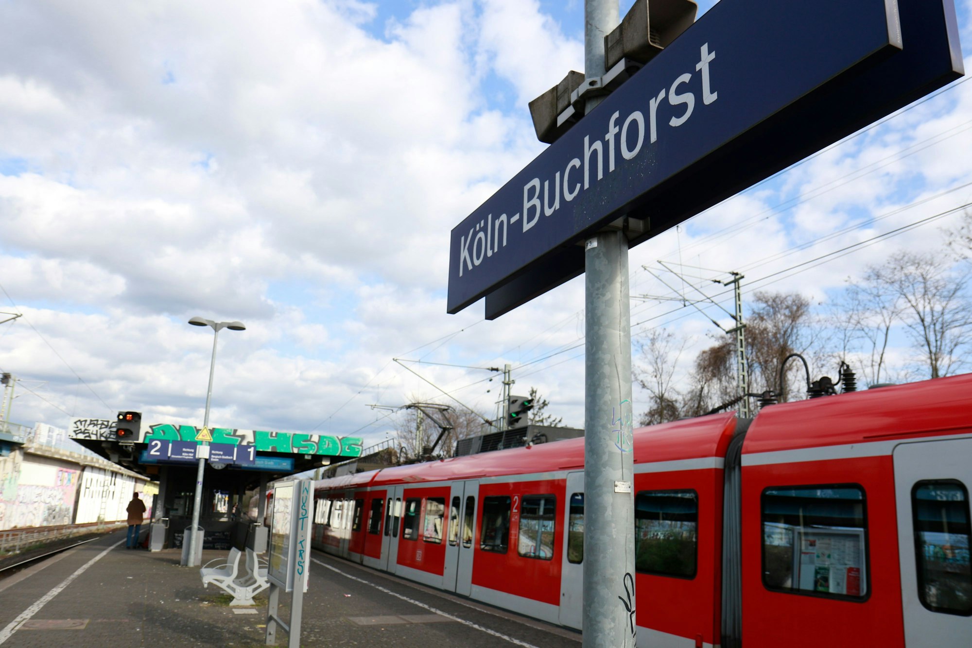 Der Bahnhof Buchforst ist zu sehen, ein Zug hält dort.