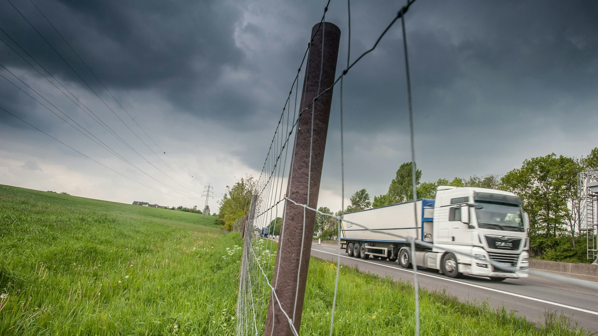 Ein Lkw fährt auf einer Autobahn an einem Feld vorbei.
