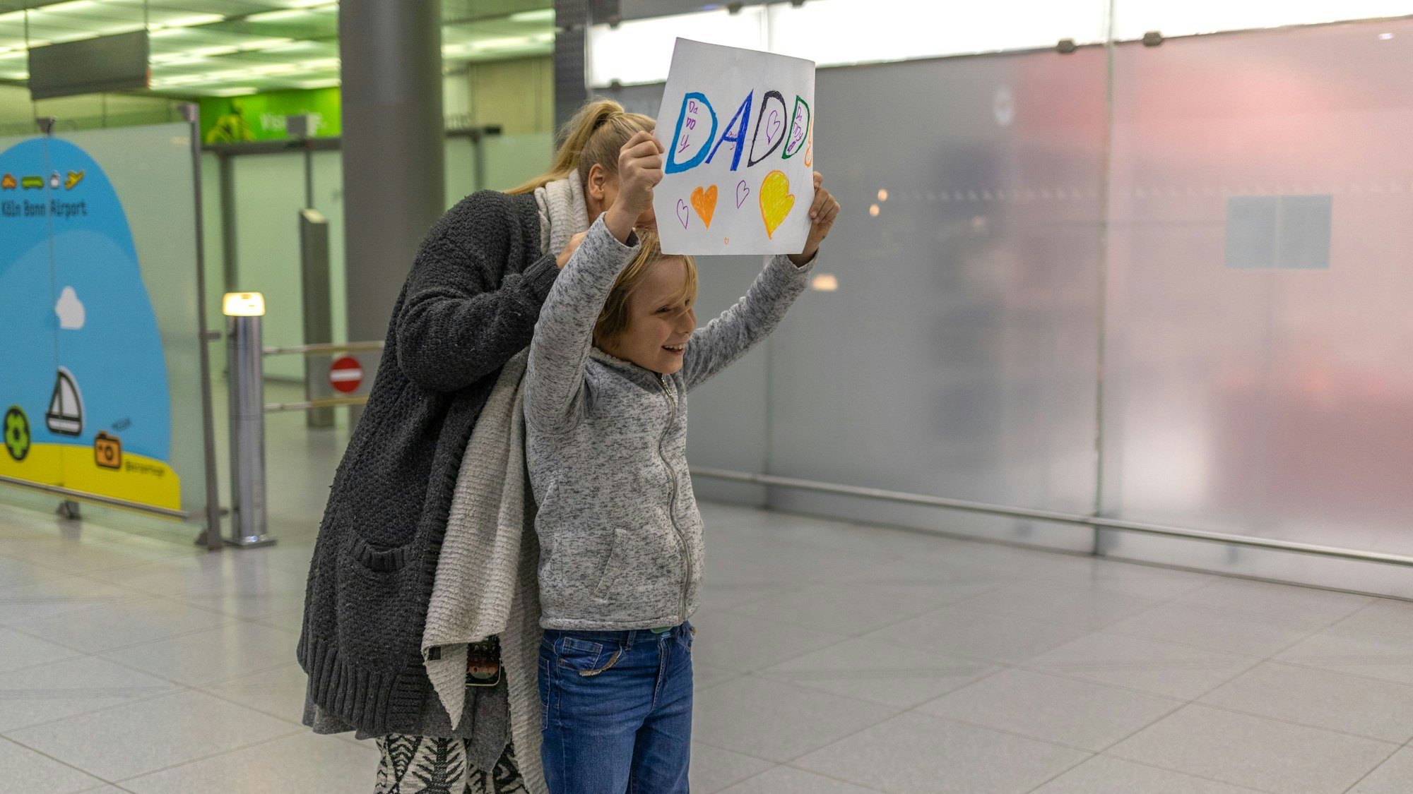 Noah hält ein Schild hoch, seine Mama steht hinter ihm.
