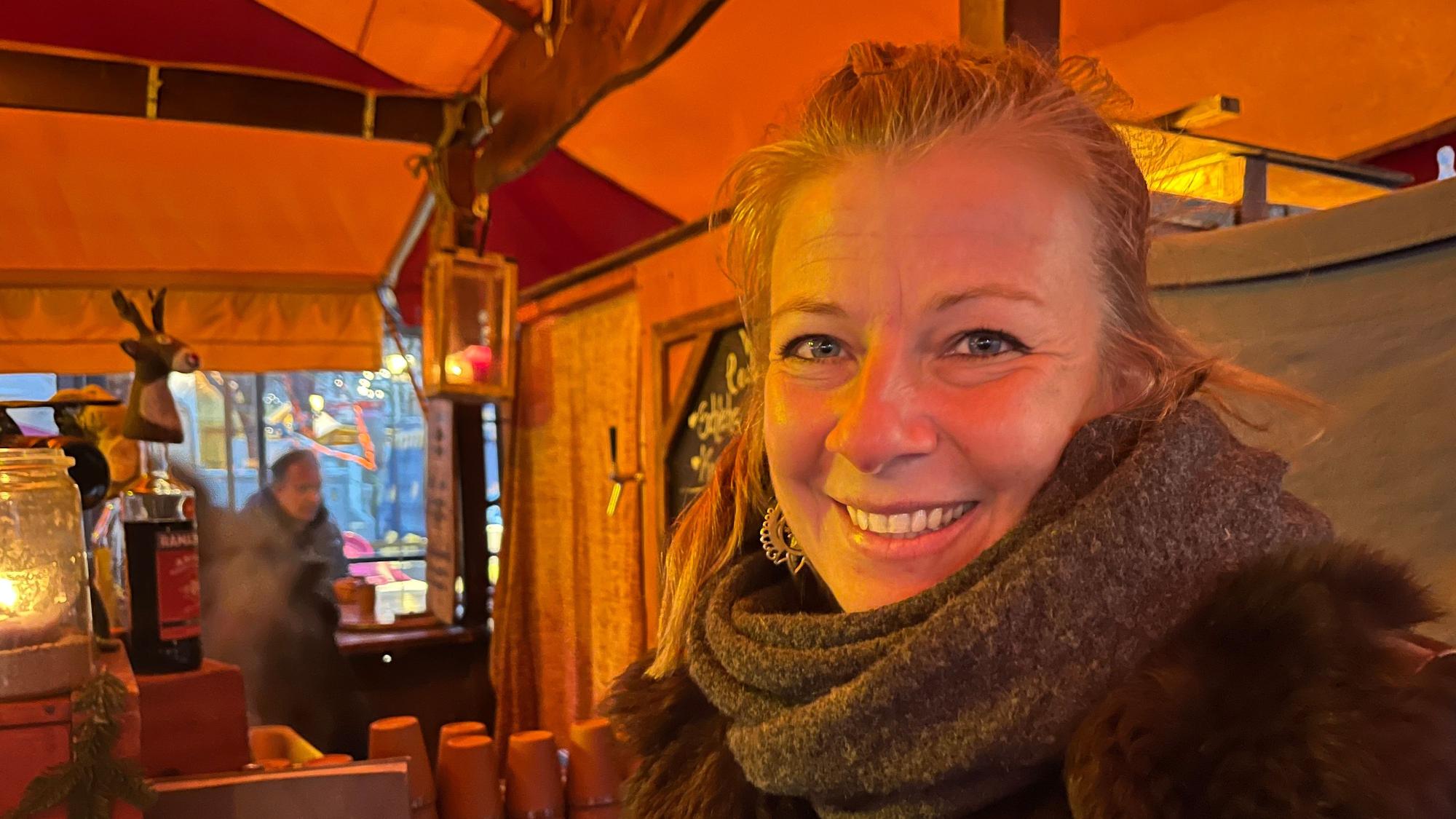 Eie Frau lächelt aus ihrem Stand in die Kamera.