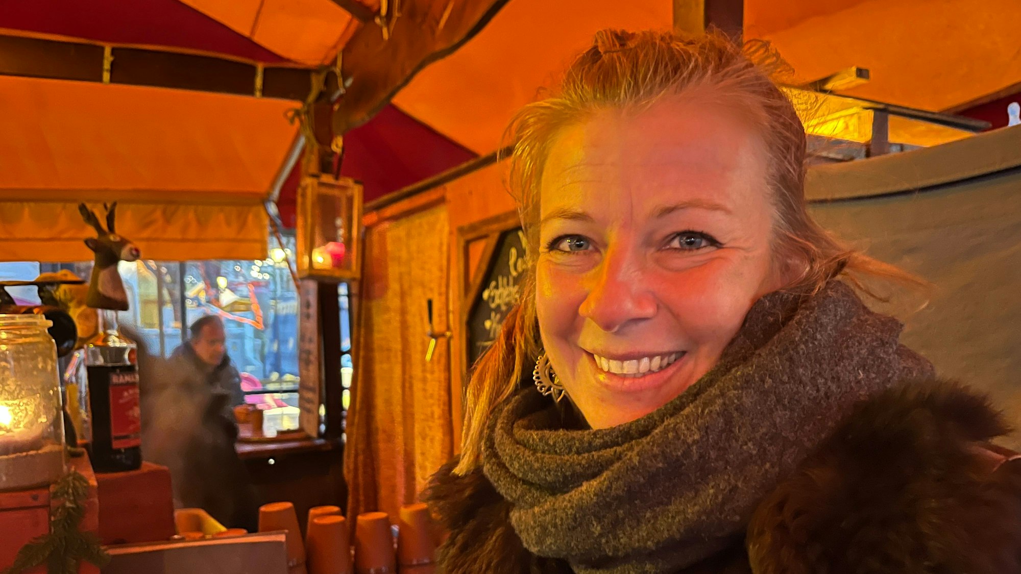 Eie Frau lächelt aus ihrem Stand in die Kamera.