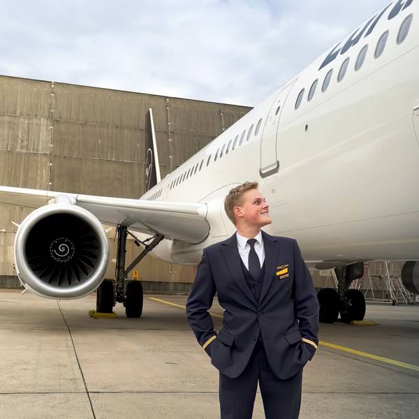 Alex Böhmer steht in seiner Uniform auf einem Rollfeld und blickt auf ein Flugzeug, das neben ihm steht.