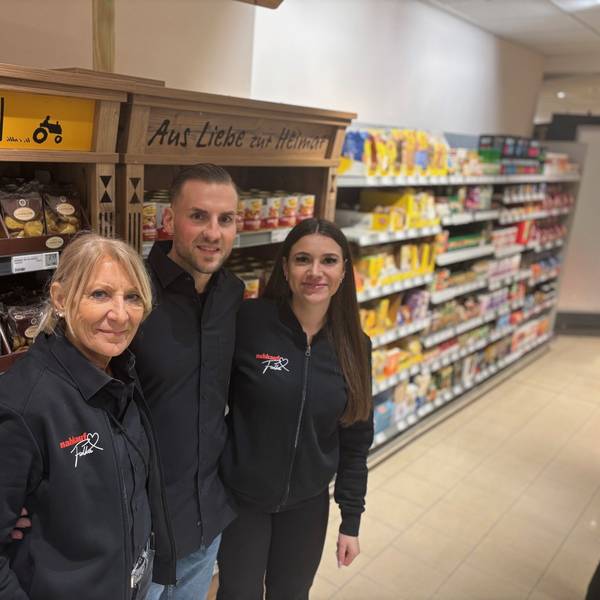Auf dem Bild ist ein Mann mit seiner Mutter und seiner Freundin vor einem Supermarktregal zu sehen.