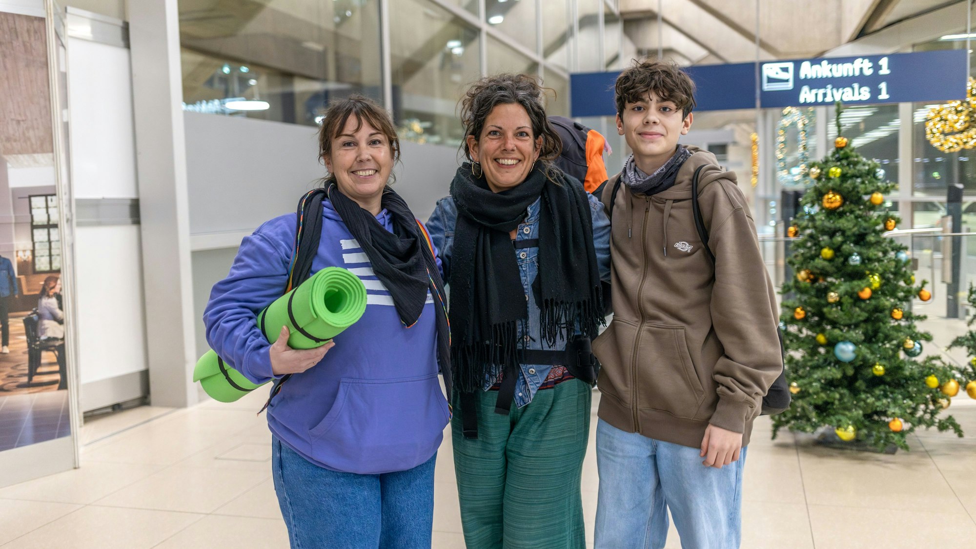 Zwei Frauen und ein Junge stehen in der Ankunftshalle des Flughafens Köln/Bonn