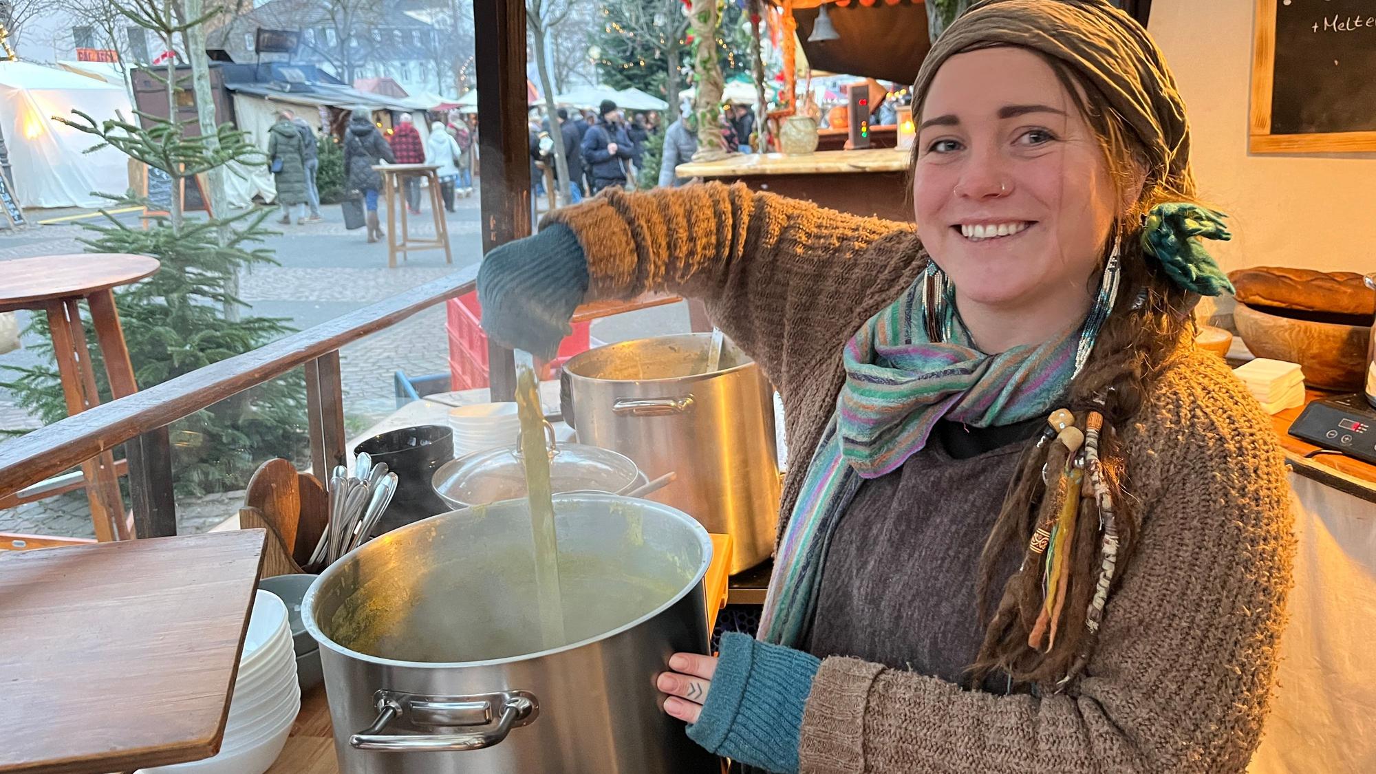 Eine junge Frau rührt in einem Suppentopf.