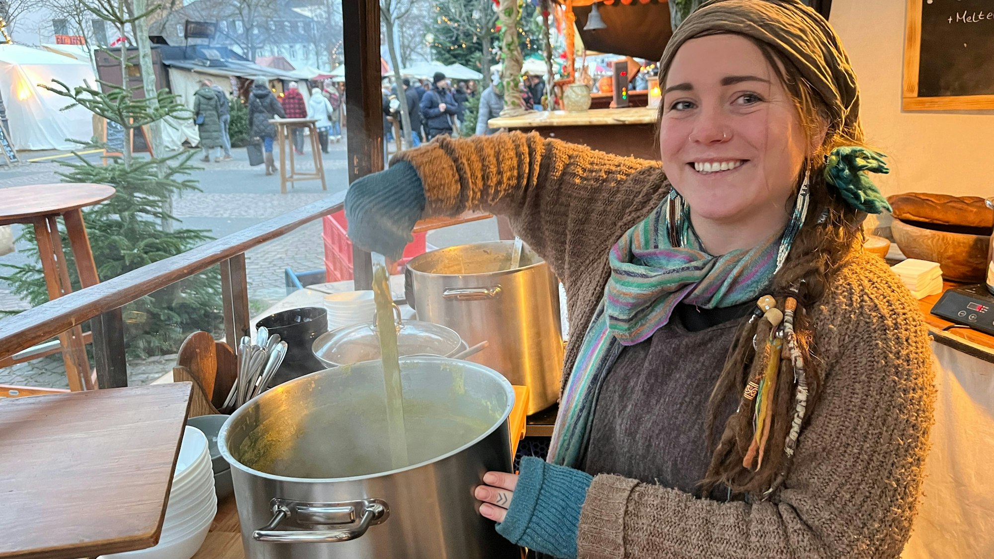 Eine junge Frau rührt in einem Suppentopf.