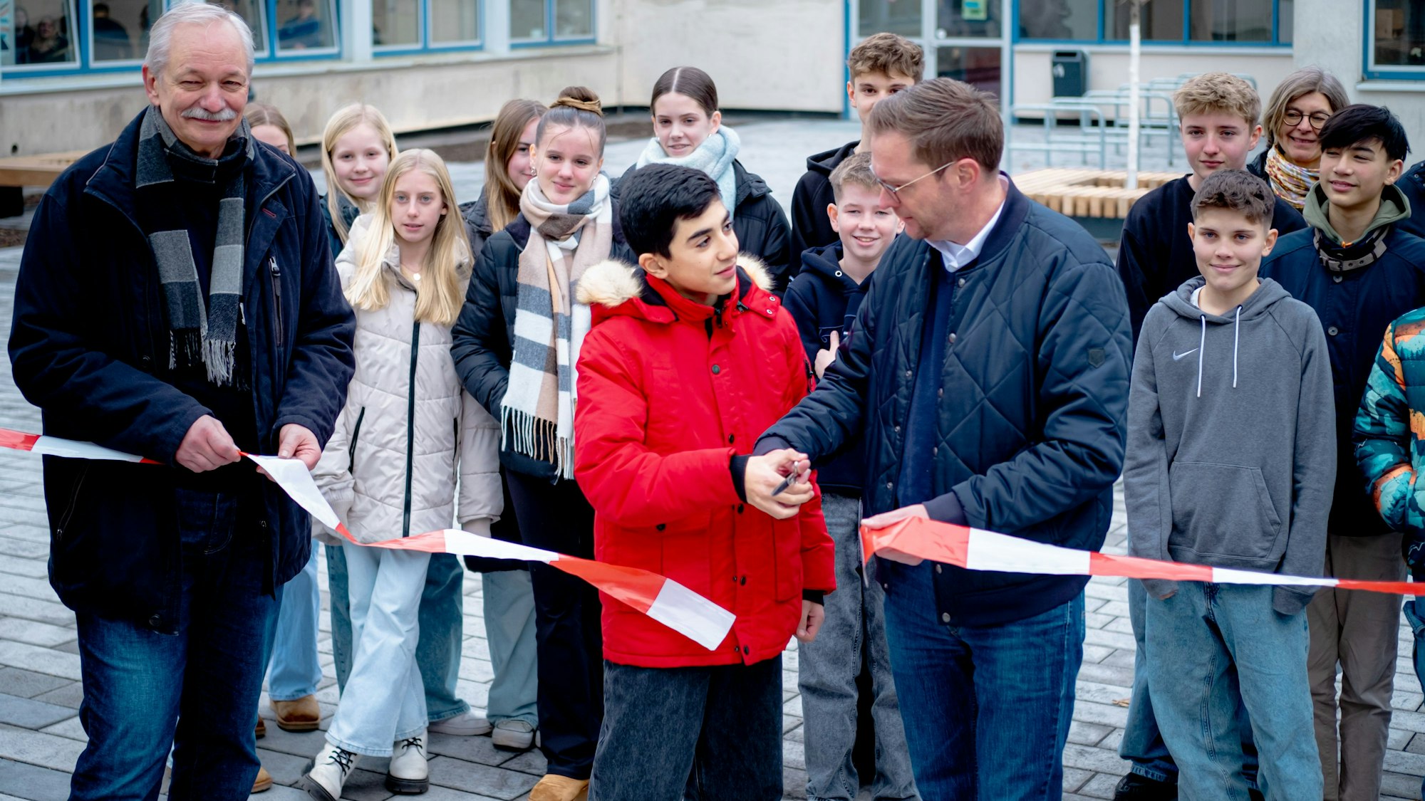 Dieter Müller, Teoman Oybak, Thore Eggert (v.l.) stehen auf dem neuen Schulhof uns schneiden zur Einweihung ein Band durch.