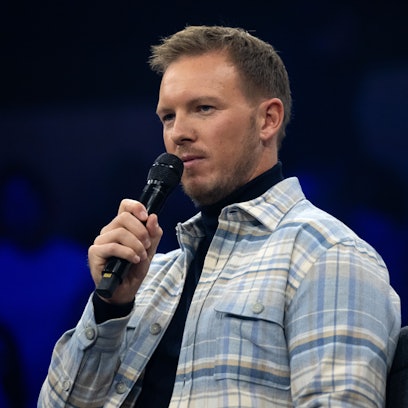 Julian Nagelsmann sitzt mit einem Handmikrofon auf einer Bühne.