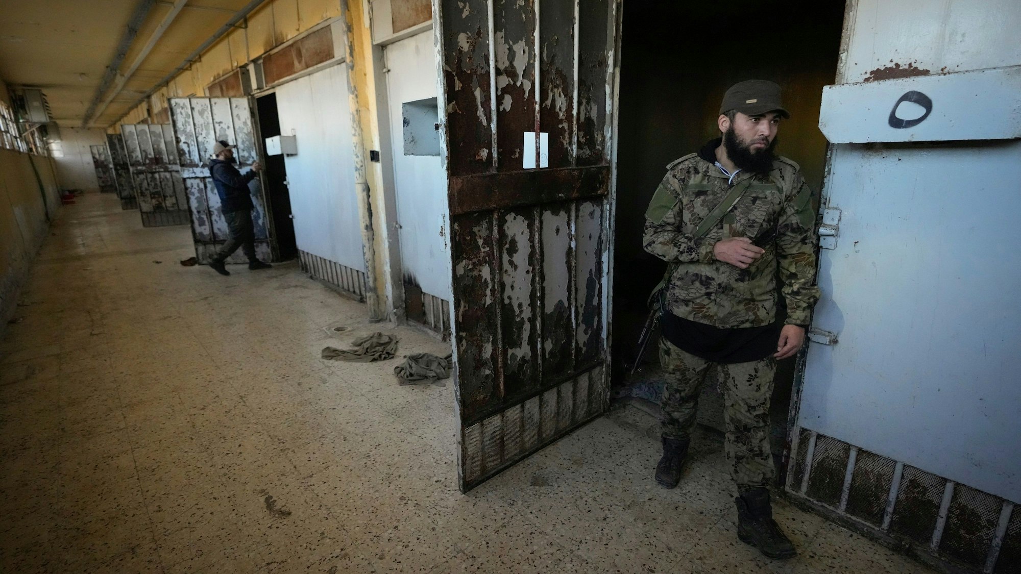 09.12.2024, Syrien, Sednayah: Zwei aufständische Kämpfer inspizieren die Zellen des berüchtigten Militärgefängnisses Saidnaja nördlich von Damaskus.