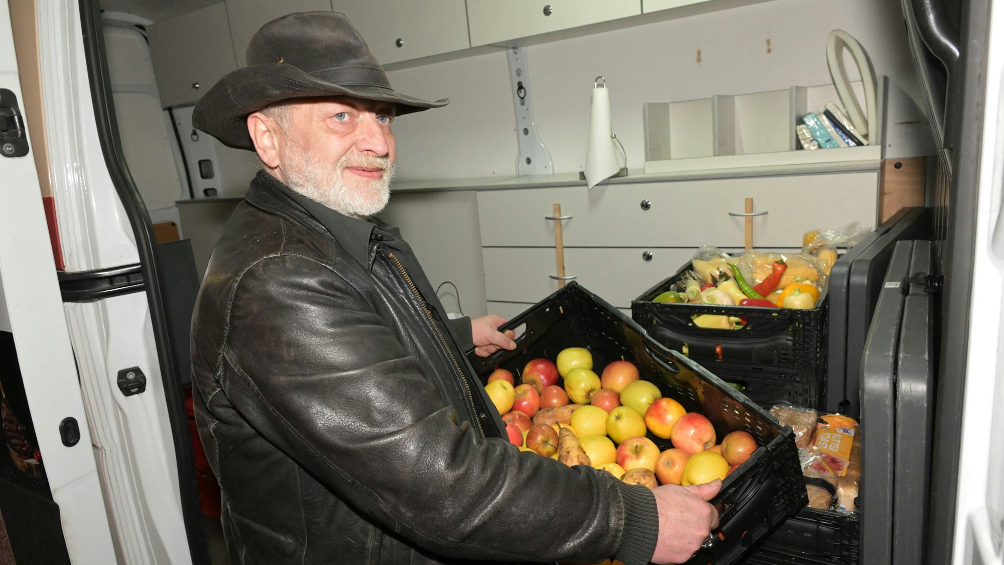 Ehrenamtler Stephan Schinkel räumt eine Kiste mit Äpfeln in den Kältebus.