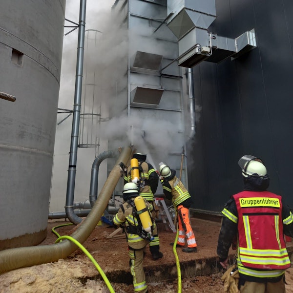 Feuerwehrleute bekämpfen das Feuer in der Filteranlage mit dem Wasser aus einem Schlauch.