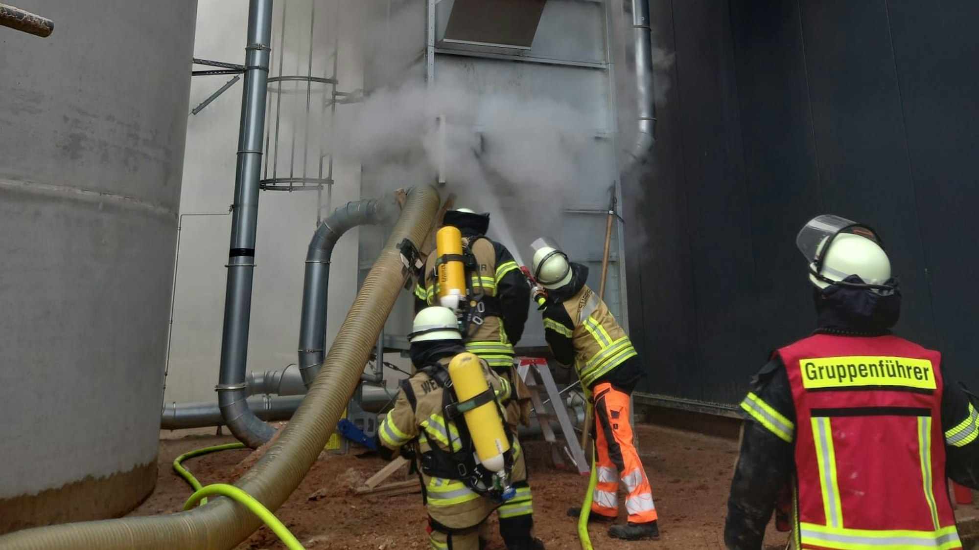 Feuerwehrleute bekämpfen das Feuer in der Filteranlage mit dem Wasser aus einem Schlauch.