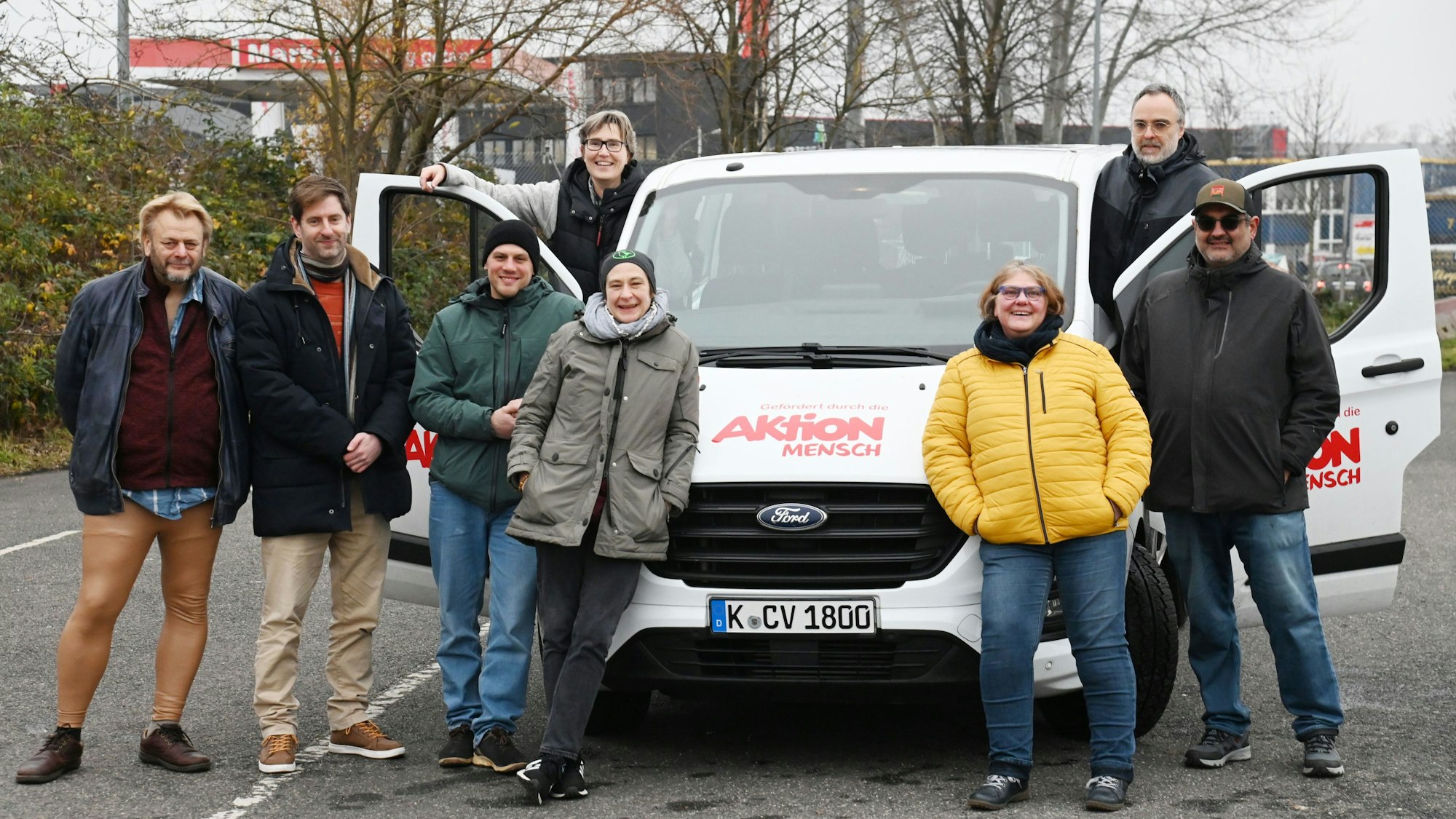 Eine Gruppe von Menschen steht rum um einen weißen Bulli.