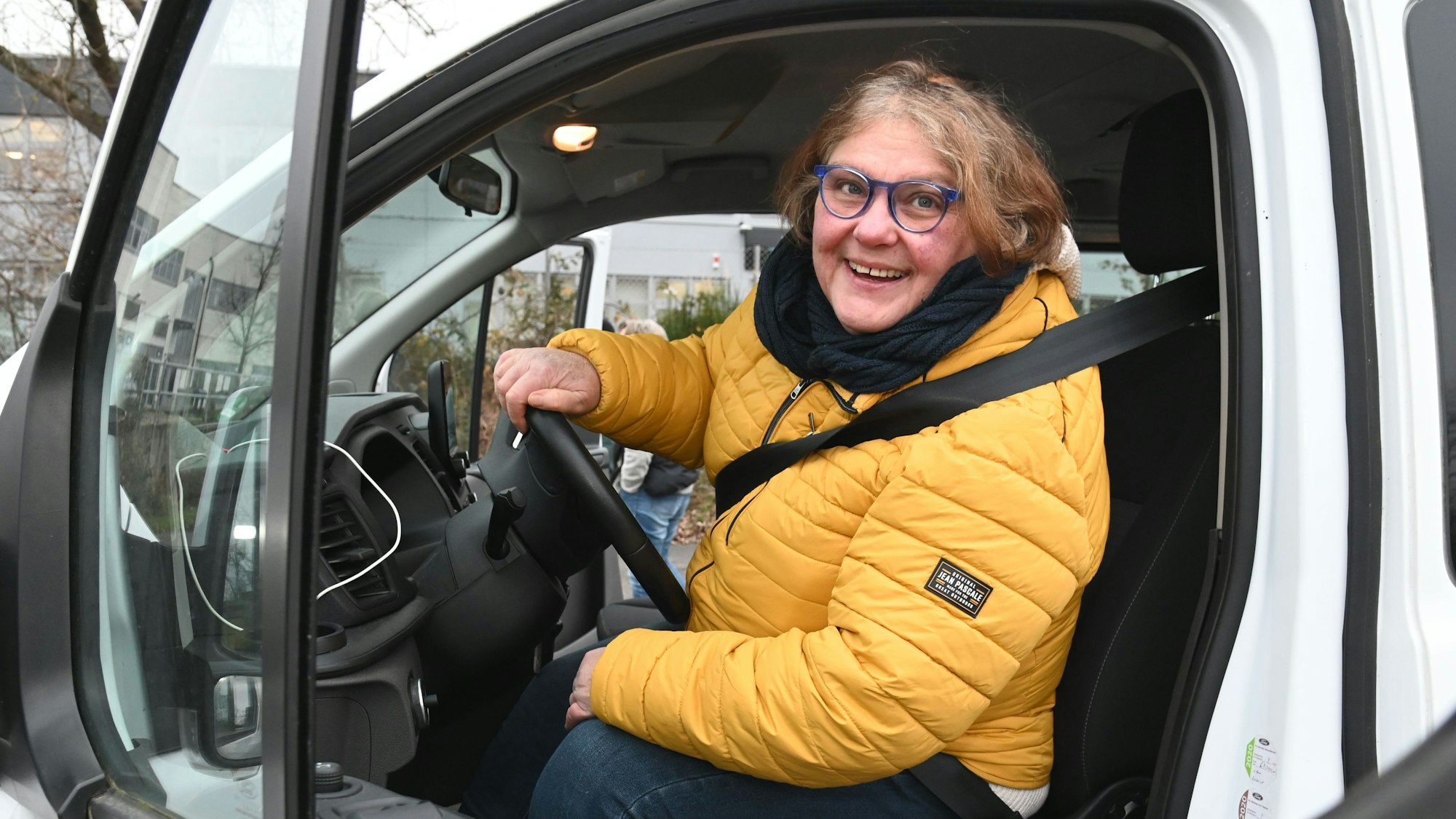 Heidi Schmitz in gelber Jacke sitzt hinterm Steuer.