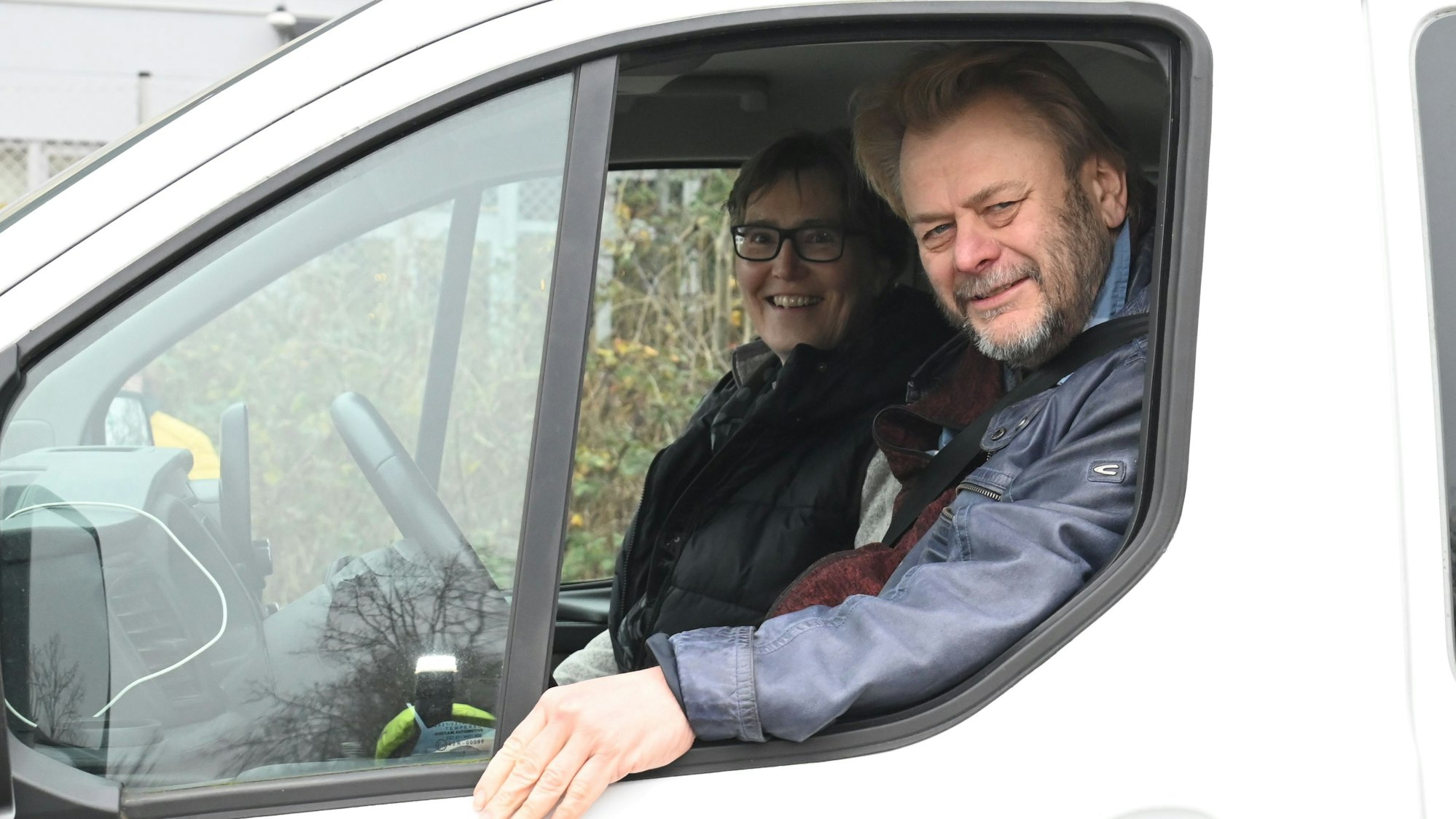 Zwei Menschen sitzen in einem Auto und schauen aus dem Fenster.