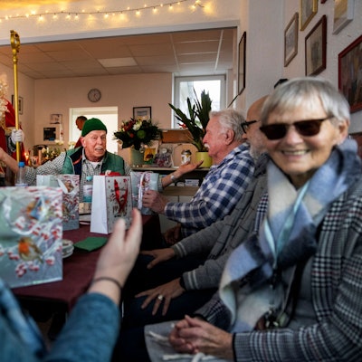 Zu Besuch bei der Weihnachtsfeier der Heimkinder-Community NRW e.V.. Astrid (links) und Annemarie (rechts) unterhalten sich. Im Hintergrund (mit grüner Mütze) Vereinsgründer Uwe Werner.