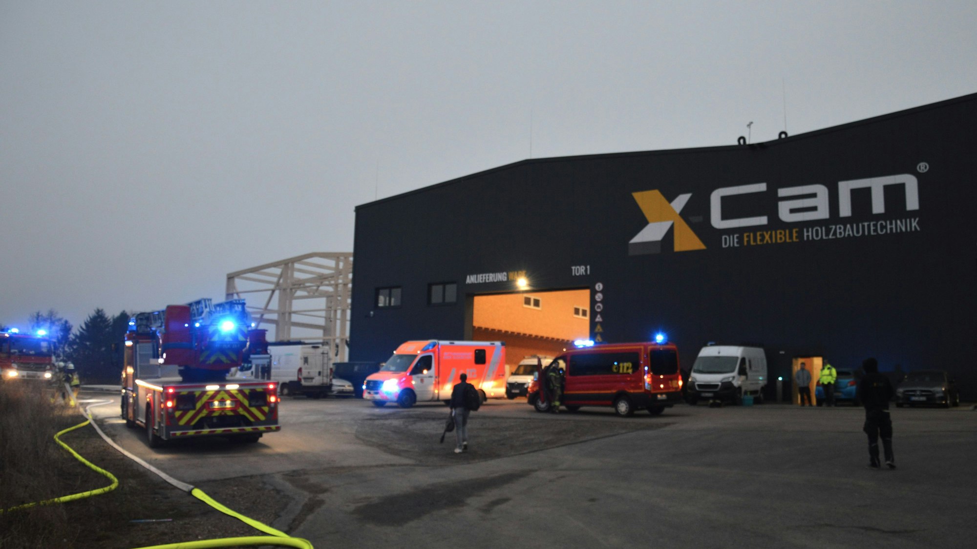 Feuerwehrfahrzeuge und ein Rettungswagen stehen vor der Halle der Firma X-Cam.
