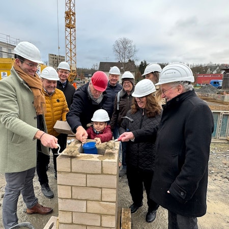 Ein Grundschüler hat Kinderwünsche für die Zukunft der Stadt Rösrath in der Zeitkapsel platziert, die anschließend eingemauert wird.