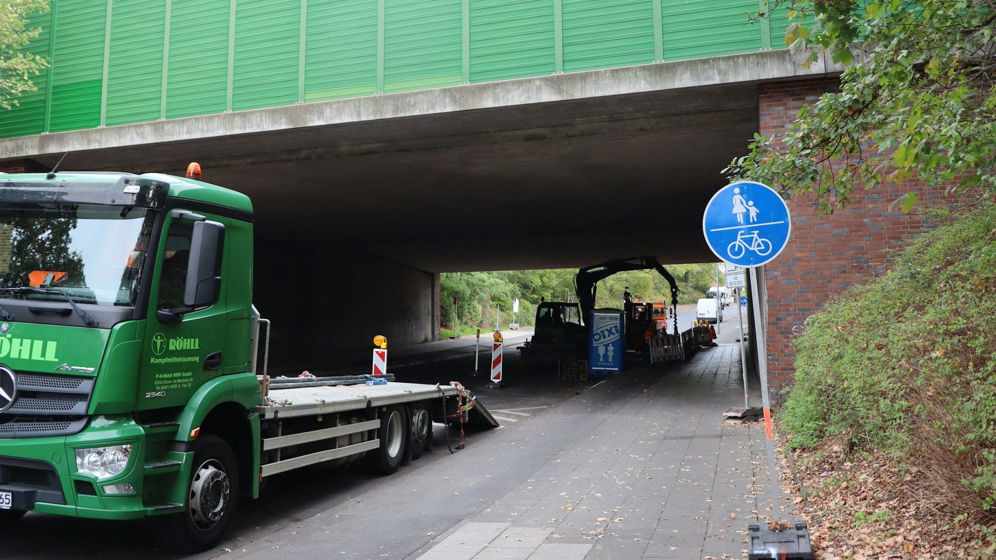 Auf dem Foto ist die Straße unter einer Autobahnbrücke zu sehen.
